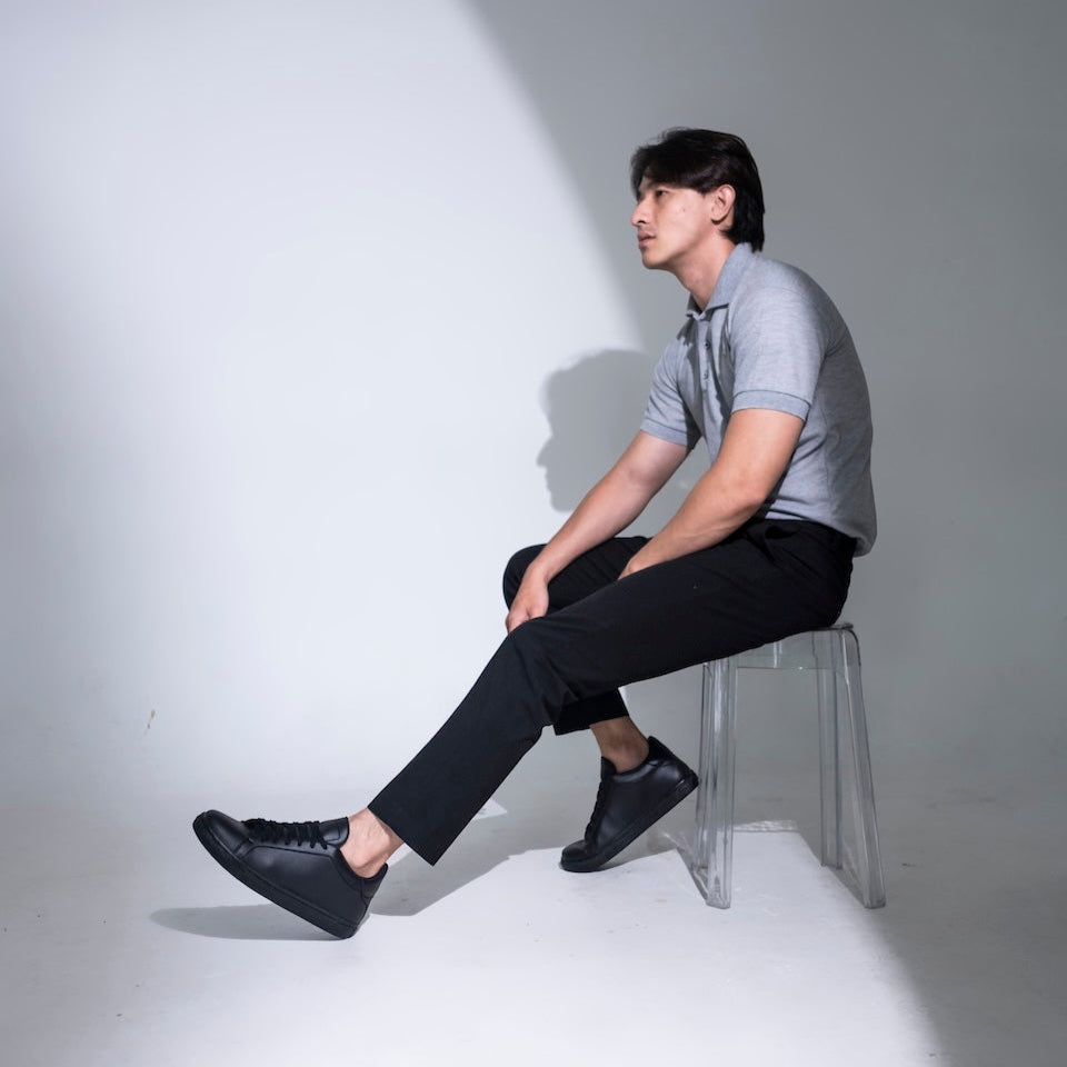 Man sitting on a stool against a white wall with a spotlight effect