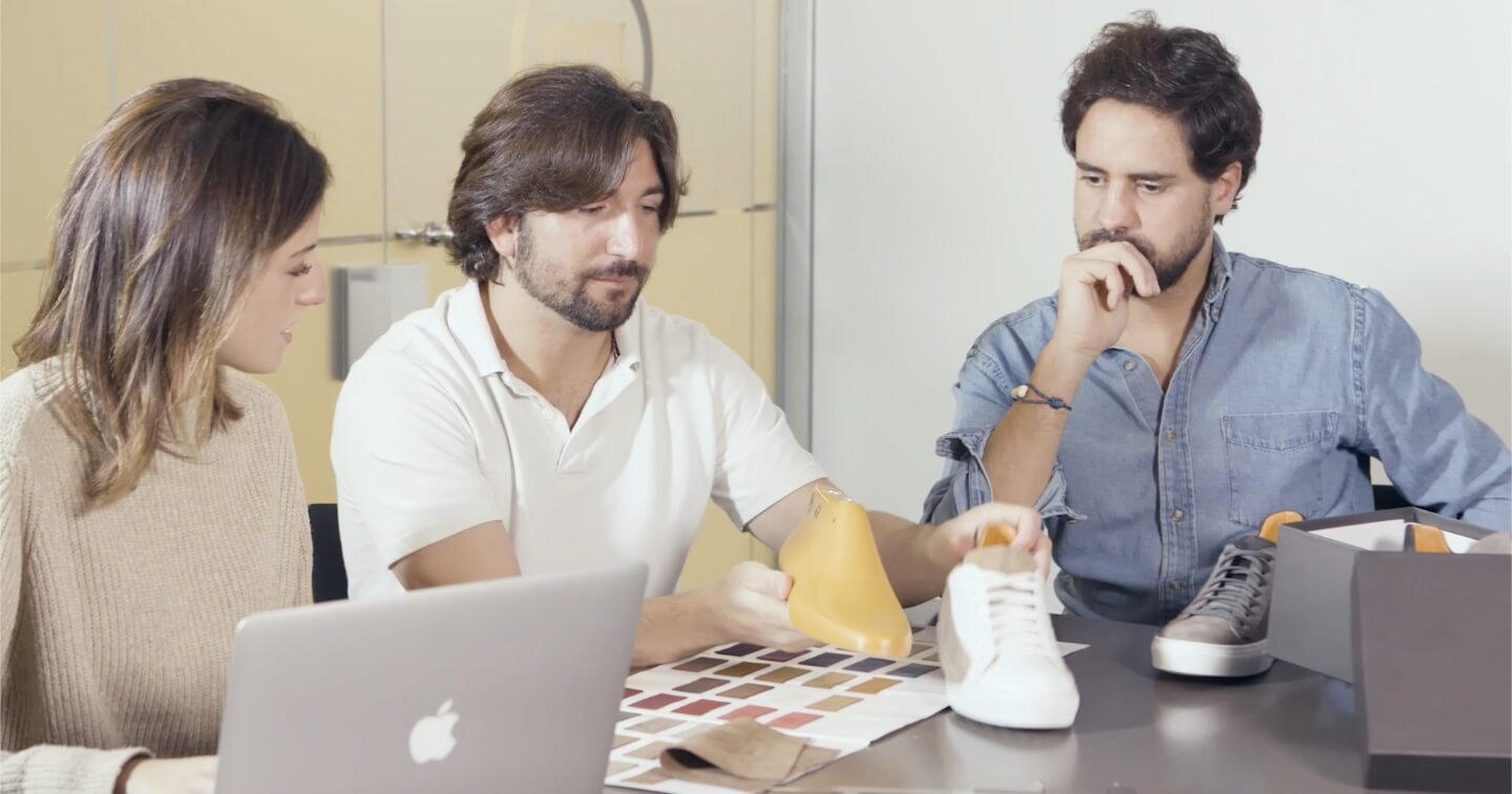 Three people working together at a table with a laptop and design materials.