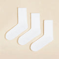 Three pairs of plain white cotton calf socks neatly arranged on a soft beige background for everyday wear