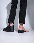 Black leather slip-on sneakers with chunky sole and minimalist design for custom leg discrepancy lift use